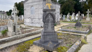 A cemetery with various tombstones and a mausoleum, surrounded by trees and pathways.