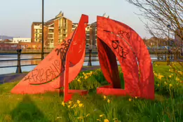 A RED METAL YOKE BY BOB SLOAN [THIS SCULPTURE IN BELFAST HAS NO NAME]-203535-1